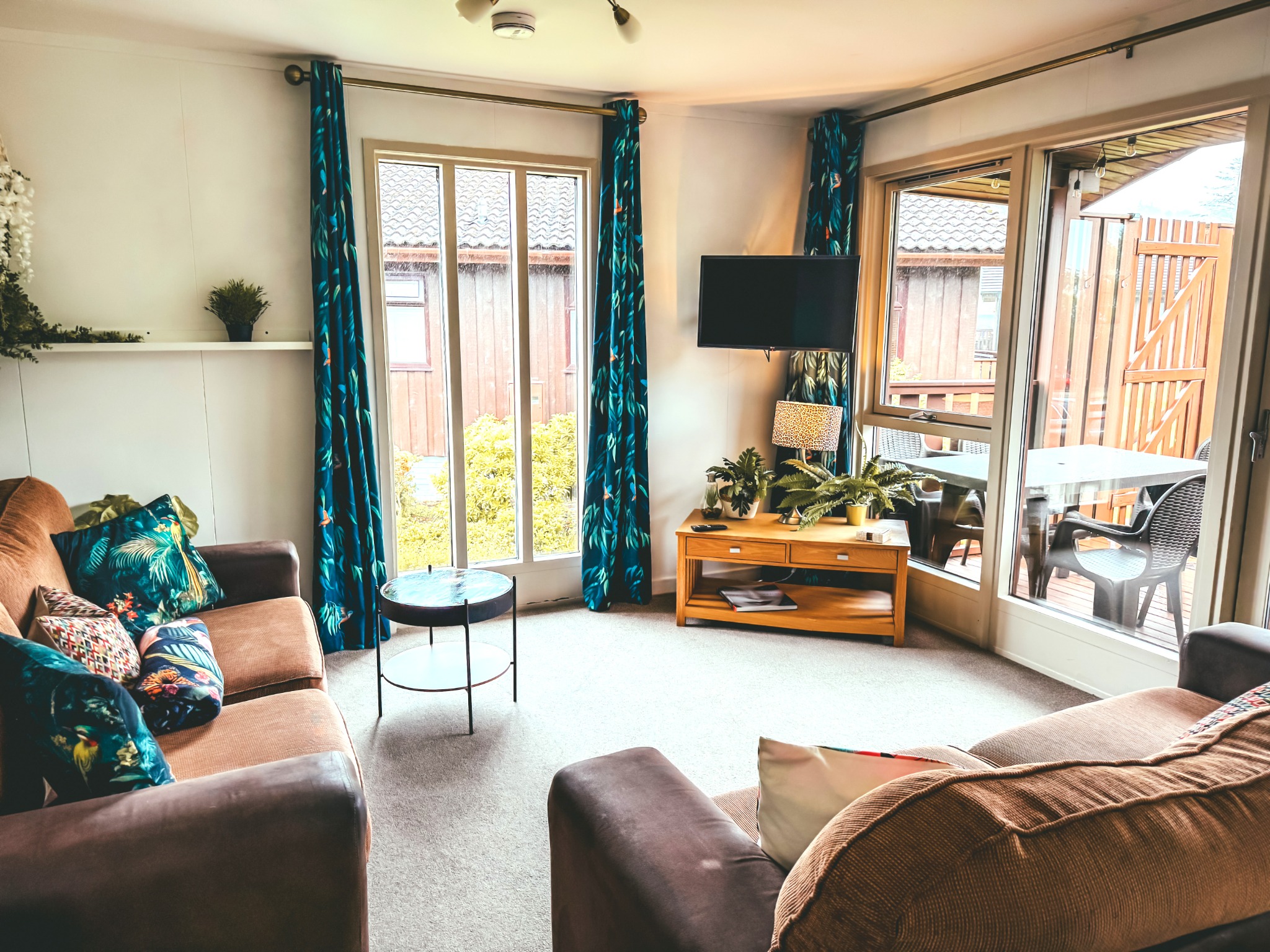 Living room at Wild Jungle Lodge with sofas, television and doors to the decking